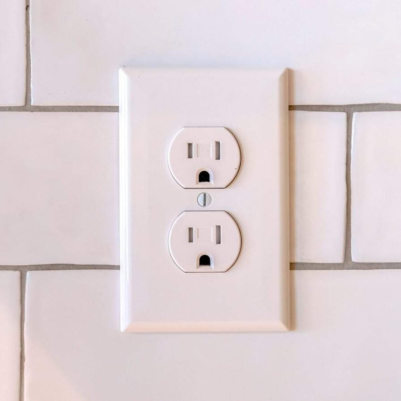 Modern electrical outlet on a white tiled wall, professional wiring service.